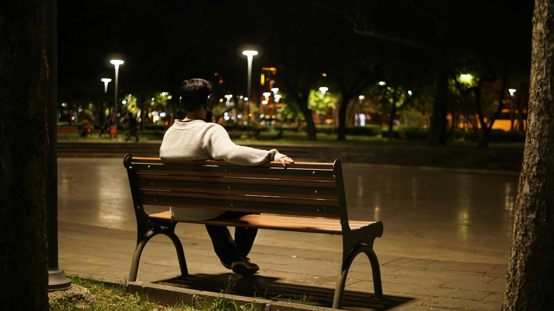 Person sitting on bench looking out over city landscape at night.