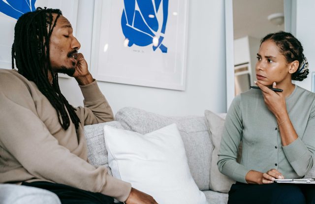 Two people sitting on a sofa chatting deep in thought