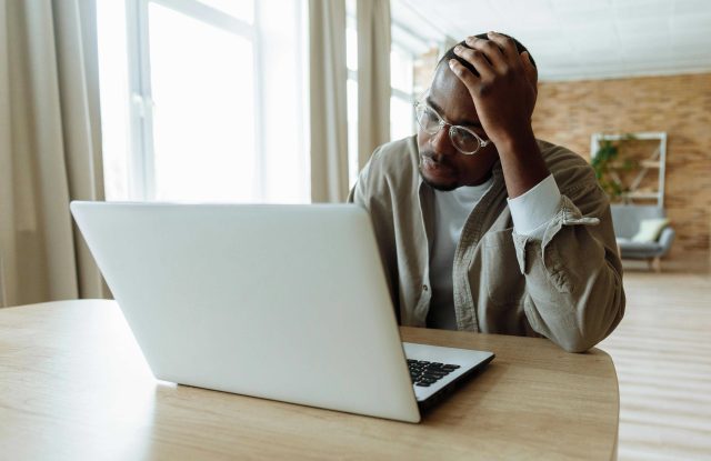 Person with head resting on hand looking at computer screen